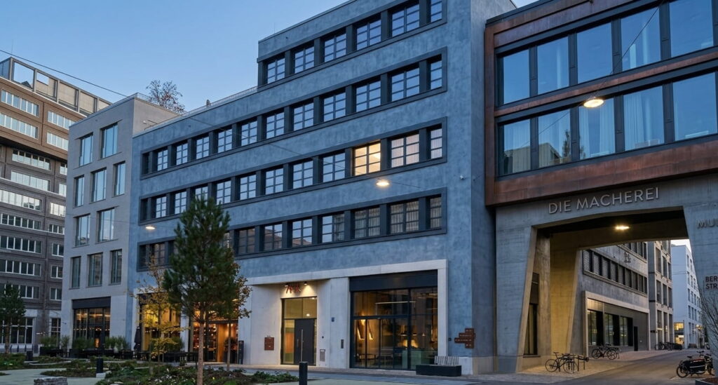 Mehrstöckiges modernes Bürogebäude mit großen Fenstern und beleuchtetem Innenhof in Berg am Laim