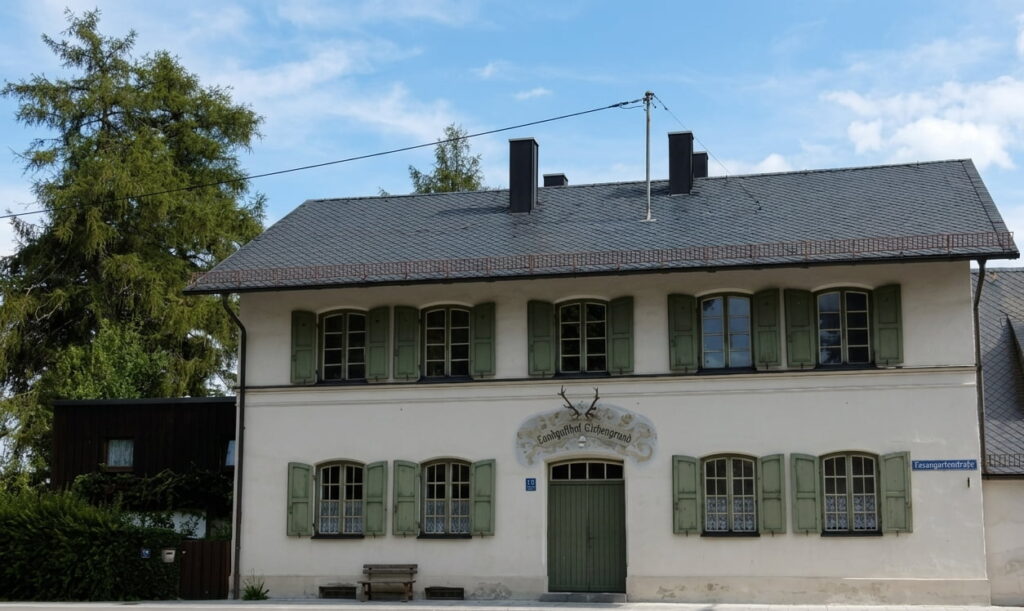 Zweigeschossiges Haus mit grün lackierten Fensterläden, Giebeldach und Hirschgeweih über dem Eingang in einer ruhigen Wohngegend
