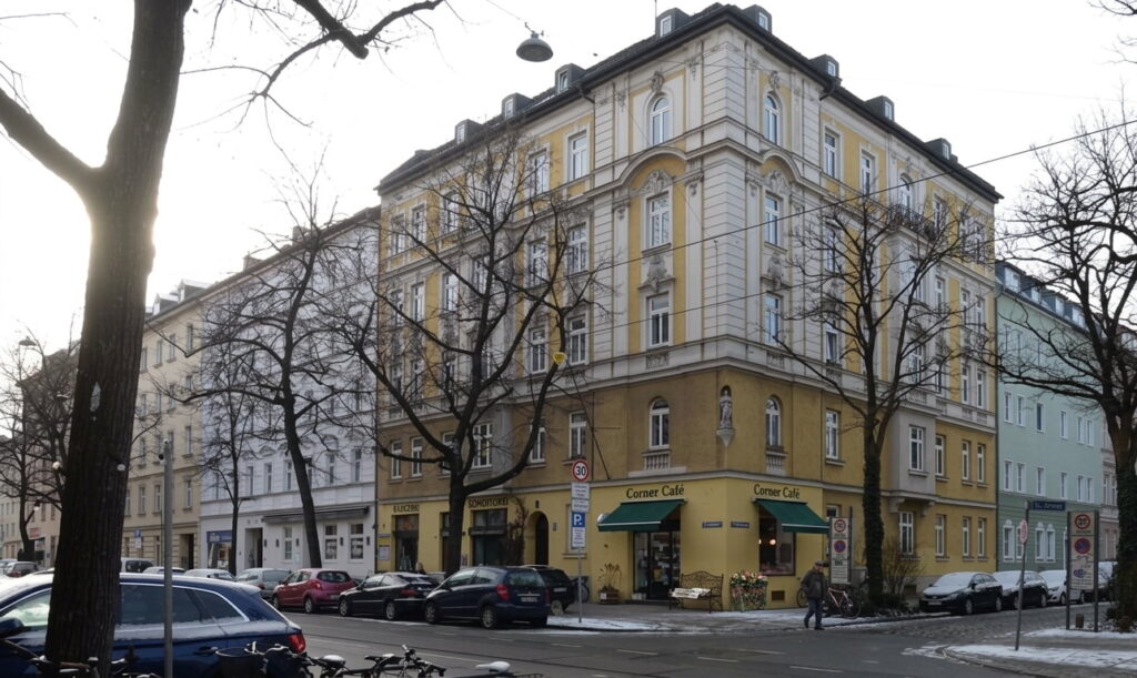 Mehrstöckiges Eckgebäude mit Café im Erdgeschoss an einer Straßenkreuzung in Haidhausen