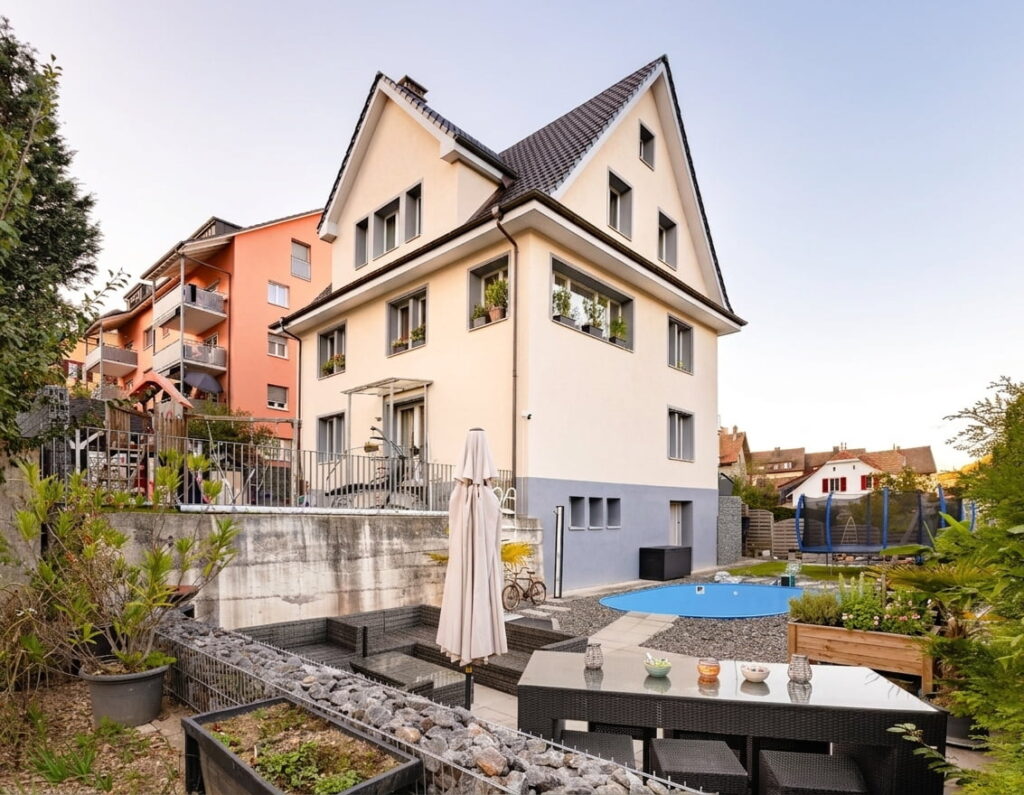 Zweistöckiges Einfamilienhaus mit Satteldach und Garten mit Pool in einem Wohngebiet