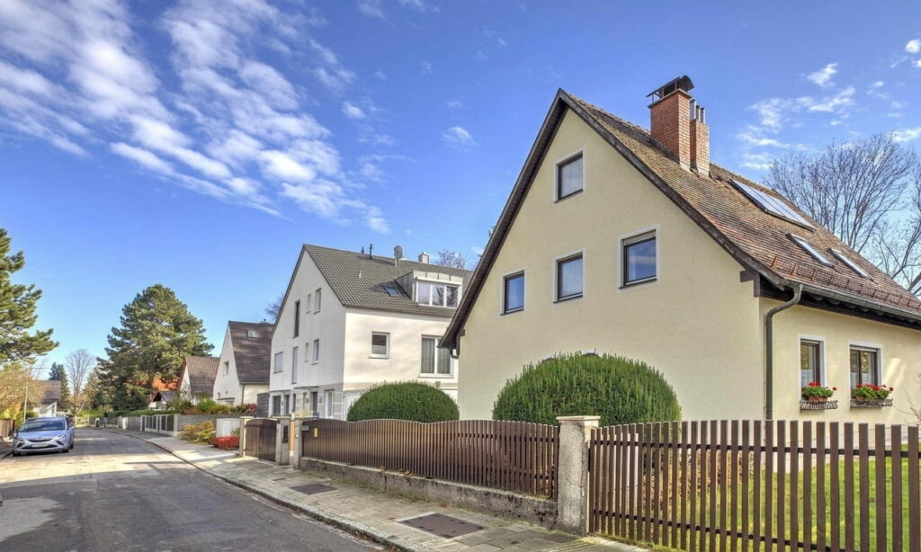 Straße mit Einfamilienhäusern und Hecken in einem ruhigen Wohngebiet bei klarem Himmel