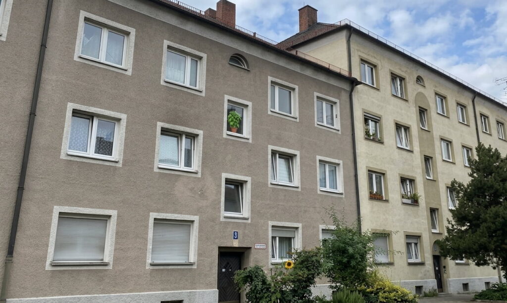 Mehrstöckiges Wohngebäude mit mehreren Fenstern und Eingangsbereich in einem Wohnviertel