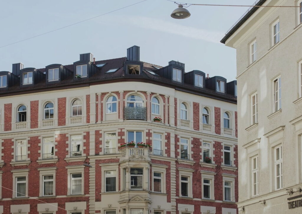 Mehrstöckiges Eckgebäude mit roten Ziegeln und weißen Fassadenelementen in der Isarvorstadt