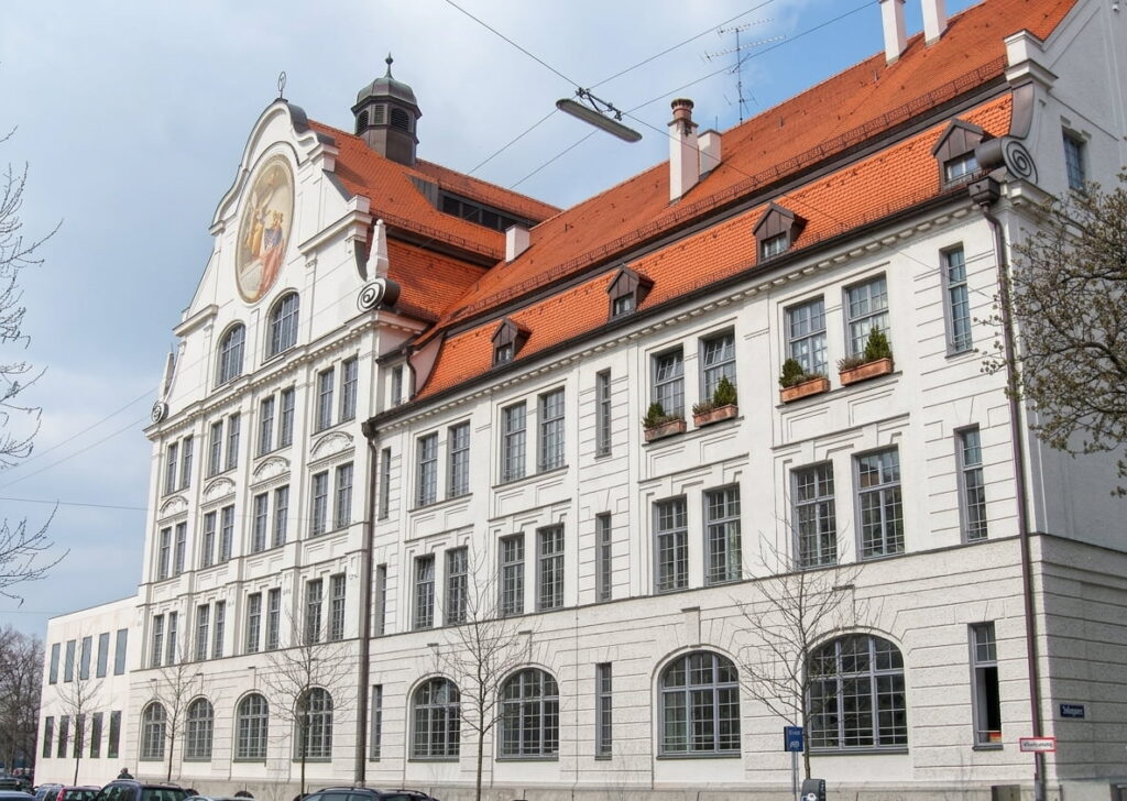 Großes historisches Gebäude mit weißer Fassade, roten Dachziegeln und mehreren Fenstern in Ludwigsvorstadt