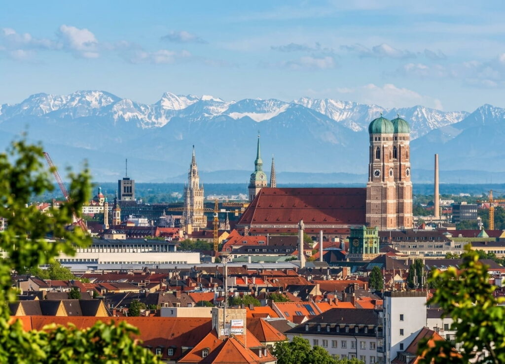 Skyline von München mit Frauenkirche und Alpenpanorama im Hintergrund – attraktiver Immobilienmarkt für den erfolgreichen Verkauf von Haus oder Wohnung in München.