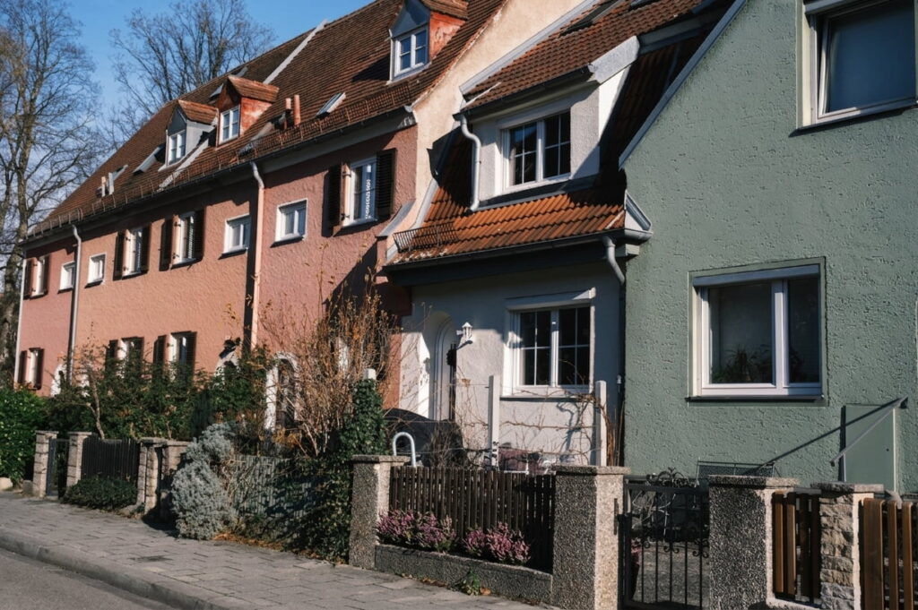 Reihe von zweistöckigen Wohnhäusern mit Satteldächern und kleinen Vorgärten an einer Straße in Ramersdorf