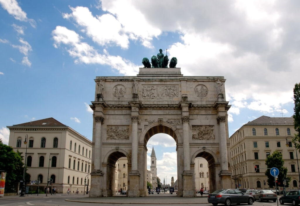 Triumphbogen mit einer Quadriga auf dem Dach, umgeben von historischen Gebäuden und Autos auf der Straße