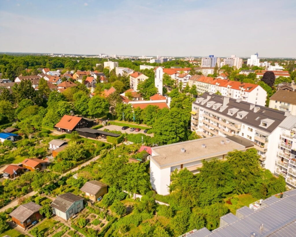 Luftaufnahme eines Wohngebiets mit Einfamilienhäusern, mehrstöckigen Wohngebäuden und viel Grün im Stadtteil Sendling-Westpark