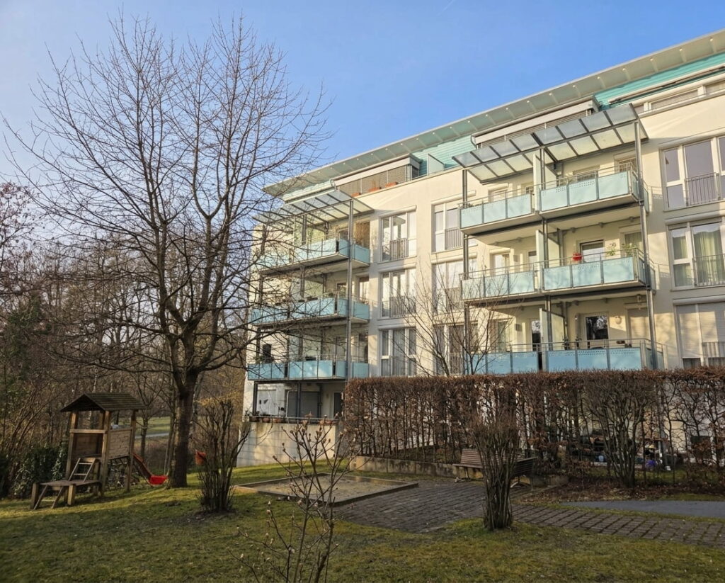 Mehrstöckiges Wohngebäude mit Balkonen und kleinem Spielplatz im Vordergrund in einer Wohnanlage in Freimann