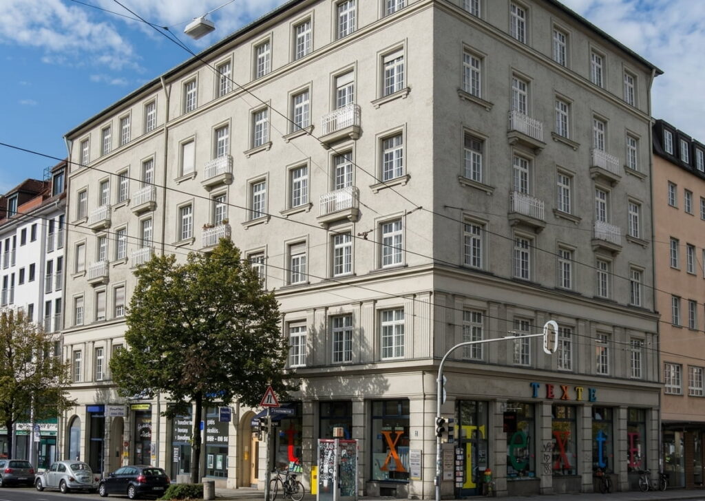 Mehrstöckiges Eckgebäude mit klassischer Fassade und Ladengeschäft im Erdgeschoss an einer belebten Straßenecke in der Isarvorstadt