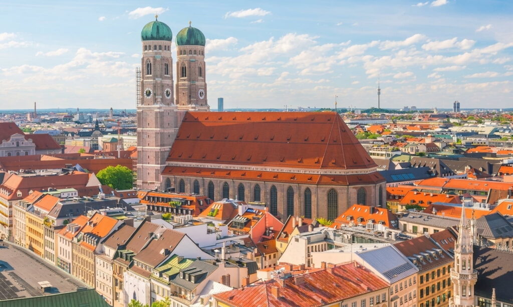 Luftaufnahme der Münchner Innenstadt mit der Frauenkirche und umliegenden historischen Gebäuden unter blauem Himmel