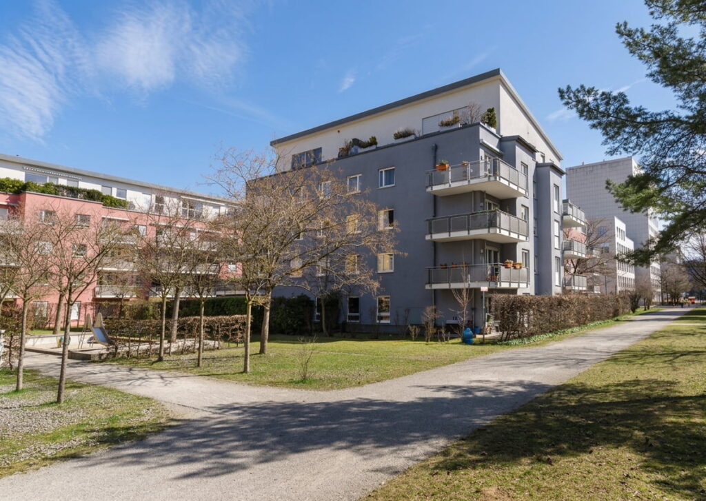 Mehrstöckiges Wohngebäude mit Balkonen in einer ruhigen Wohnanlage in Schwabing bei klarem Himmel