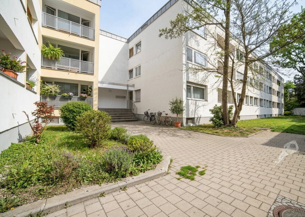 Mehrstöckiges Wohngebäude mit Balkonen, Fahrradständer und gepflastertem Innenhof in Schwabing-West