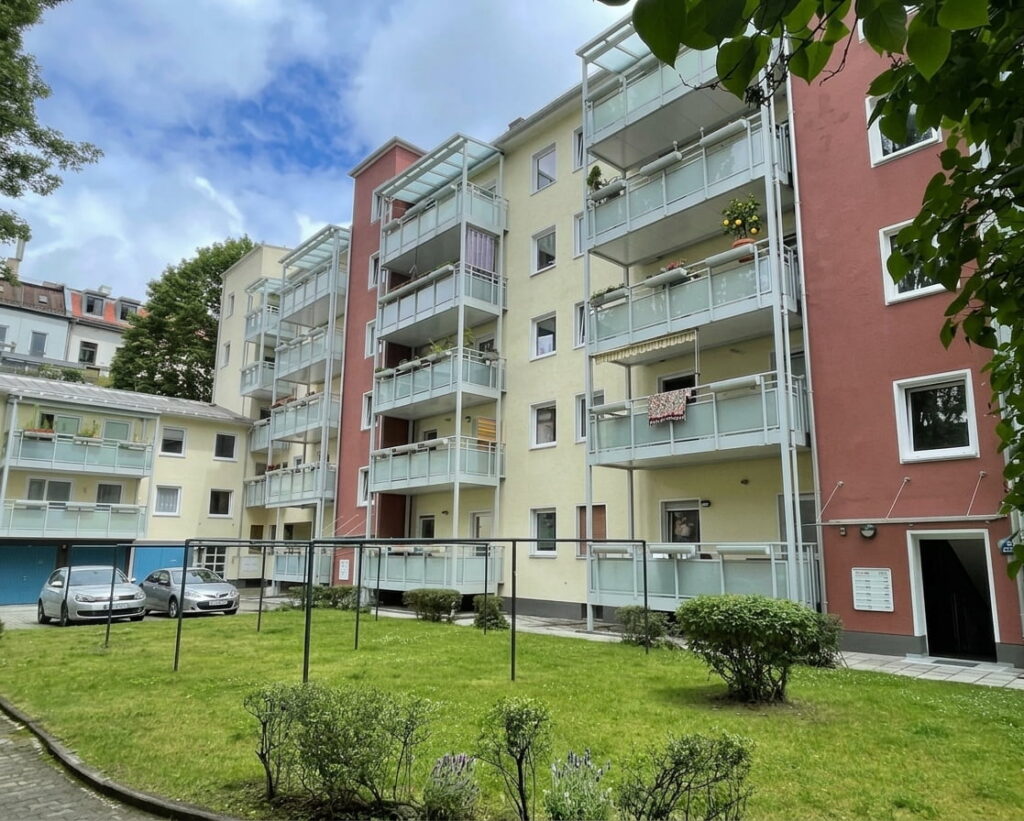 Mehrstöckiges Wohngebäude mit Balkonen und gepflegtem Innenhof mit Wäscheleinen und Grünflächen