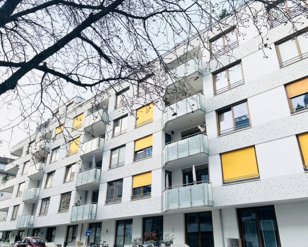 Mehrstöckiges Wohnhaus mit mehreren Balkonen und gelben Rollläden in Sendling