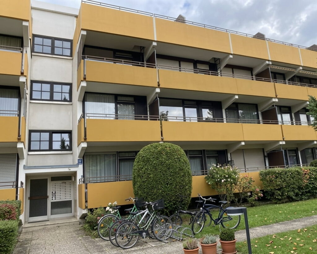Mehrstöckiges Wohngebäude mit gelben Balkonen und Fahrradständer im Vordergrund in Am Hart