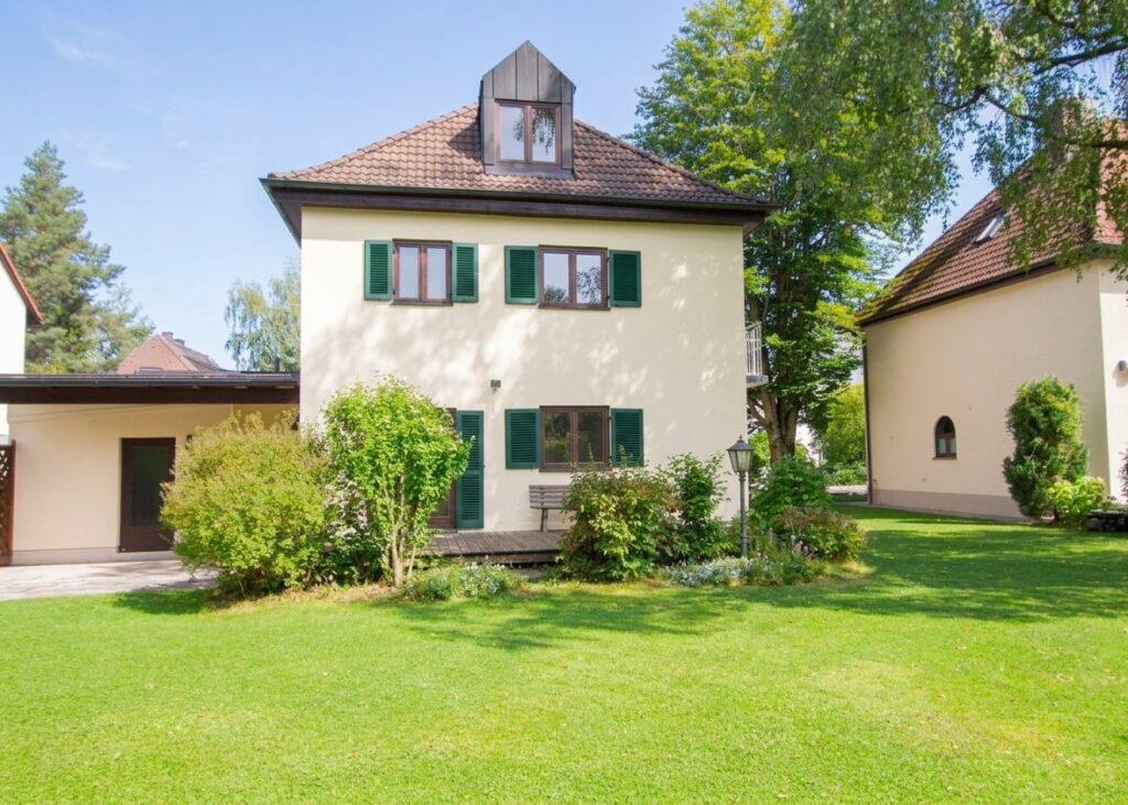 Zweistöckiges Haus mit Satteldach, grünen Fensterläden und großem Garten in Harlaching